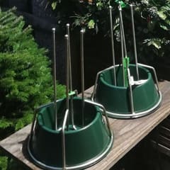 Green Christmas tree stands with steel prongs for sale at the Pitchcombe Fresh hut